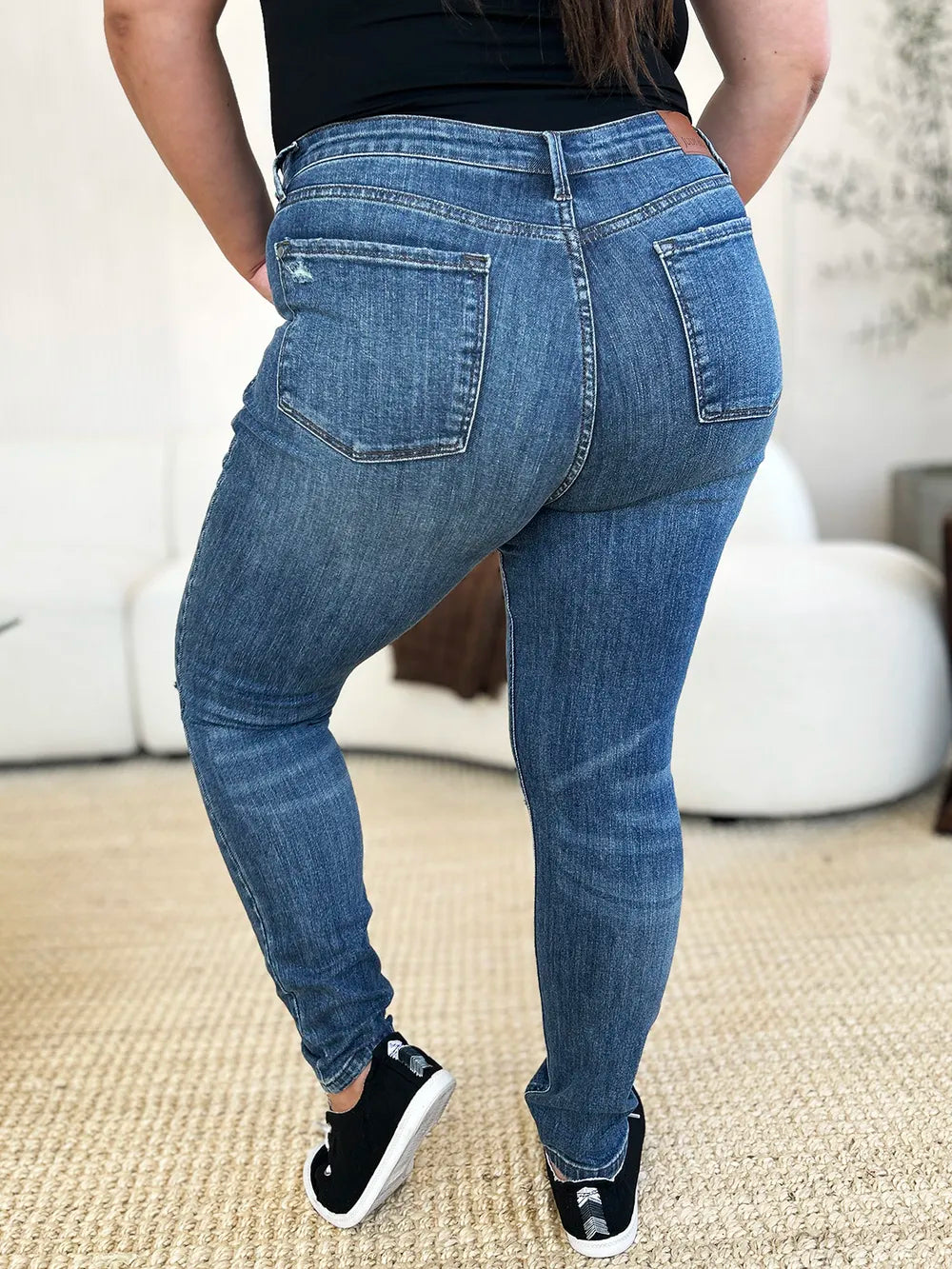 Dark blue mid-waist slim jeans with distressed knees and back pockets
