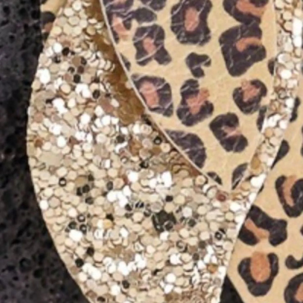 Close-up of gold leopard print and gold glitter leaf drop earrings