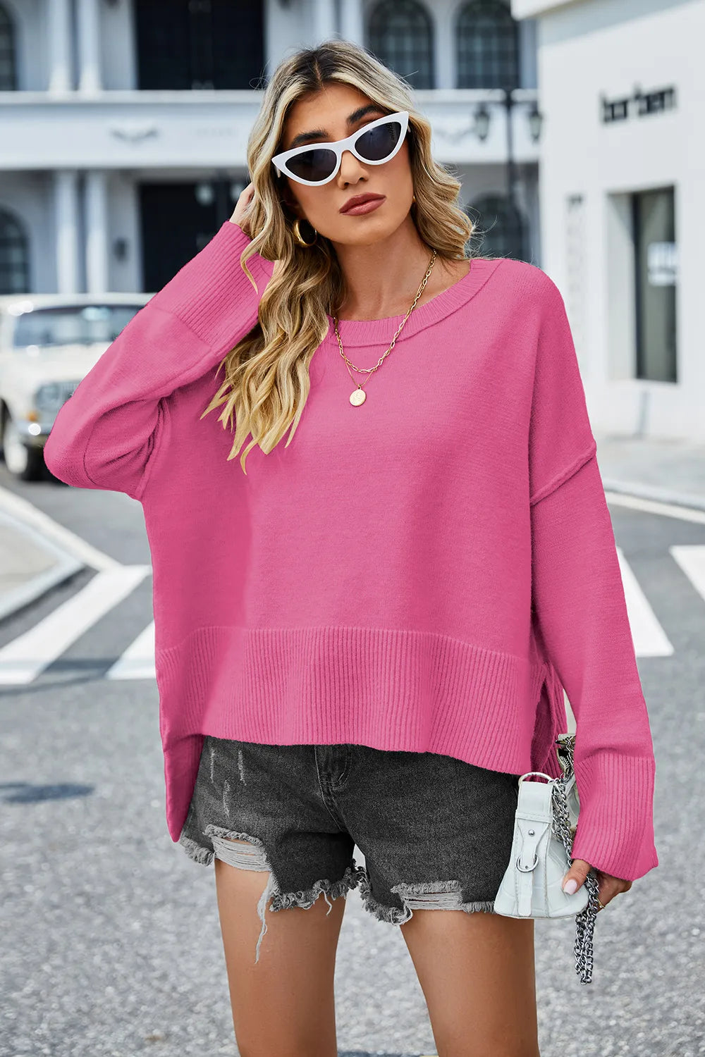 Hot pink long-sleeve sweater with round neck and ribbed high-low hem detail.