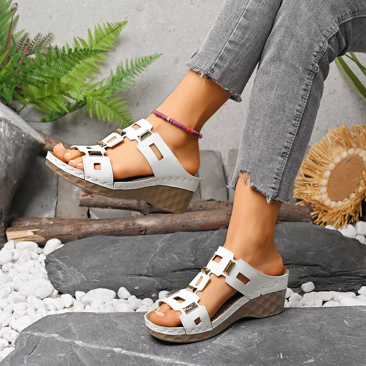 White open-toe wedge sandal with square cutout straps and gold-tone buckles, textured sole.