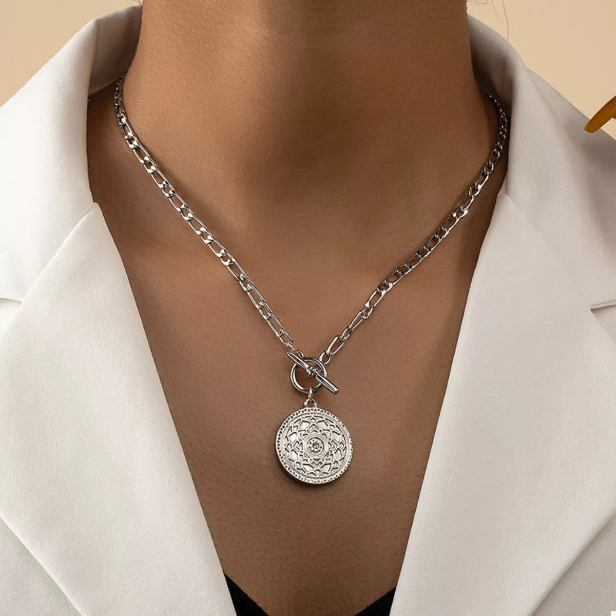 Silver chain link necklace with vintage coin pendant and bow clasp at center