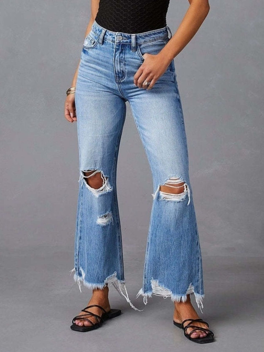 Light blue distressed flare jeans with raw hem and ripped knees, front view