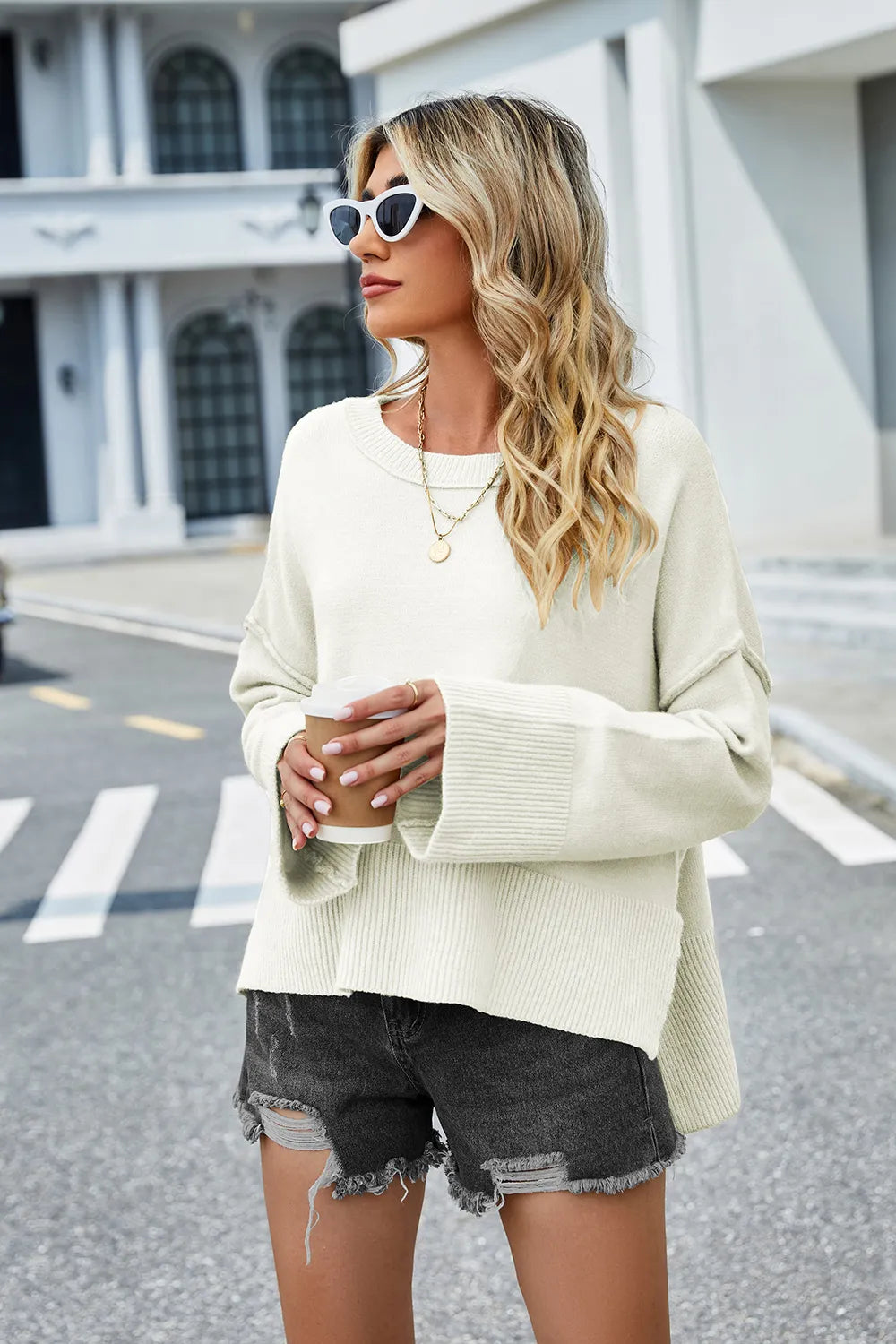 Cream round-neck sweater with long sleeves and ribbed high-low hem slit.