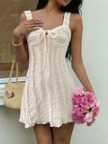 Cream textured mini dress with sweetheart neckline, bow tie front, ruffle-trim straps
