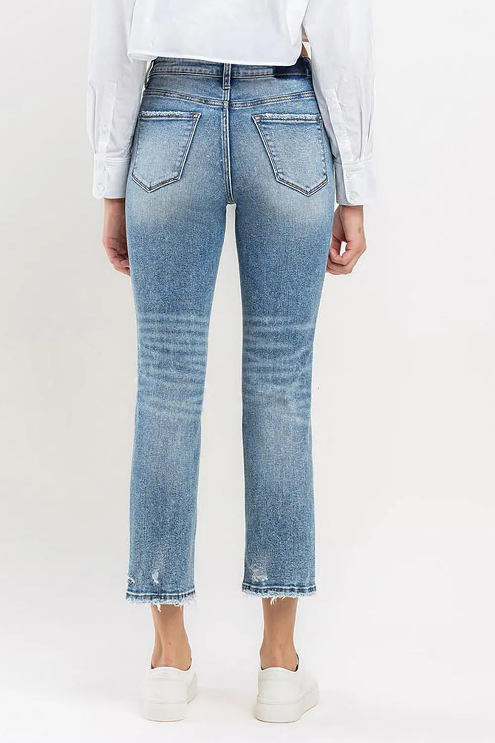 Medium wash high-rise slim straight jeans, back view; straight legs with frayed hem
