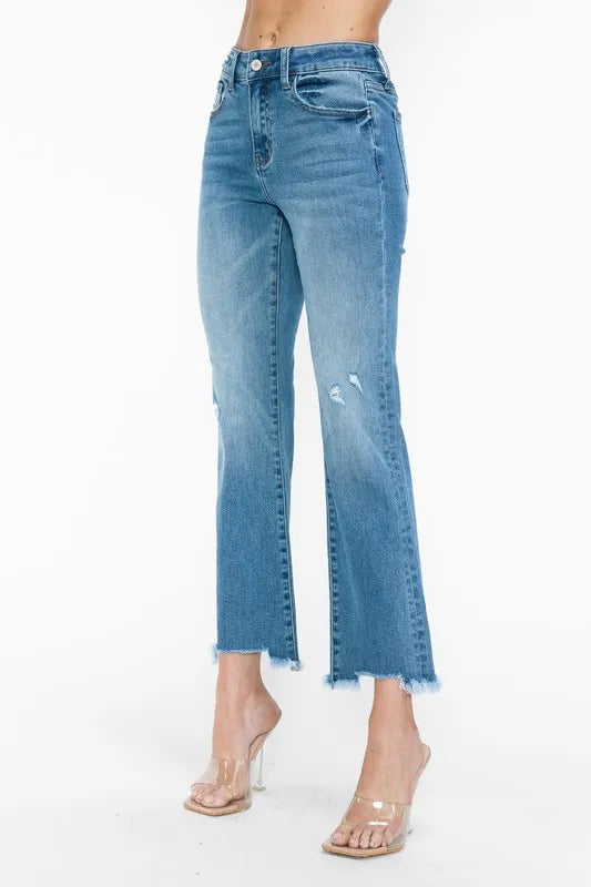 Front close-up of medium-wash mid-rise jeans with raw frayed hem and distressed stains
