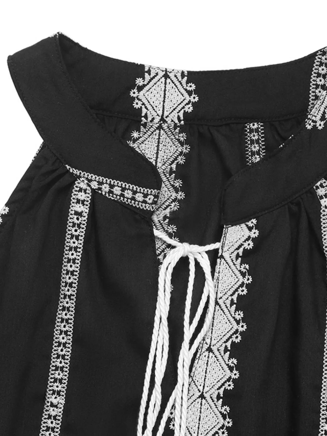 Black halter tank neckline with white embroidery, tie detail, and tassels