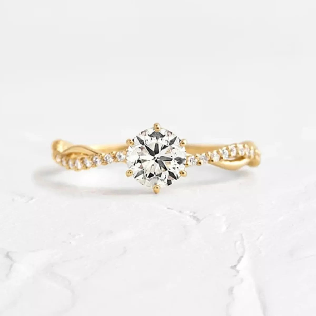Gold-tone zircon engagement ring with round center stone and prong-set side pavé