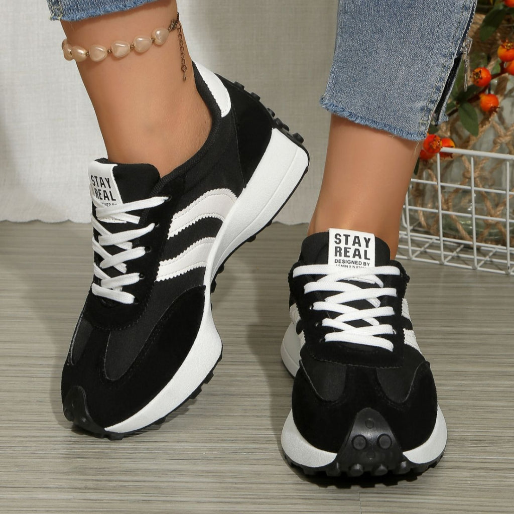 Black lace-up sneakers with white striped panels, round toe, thick white sole