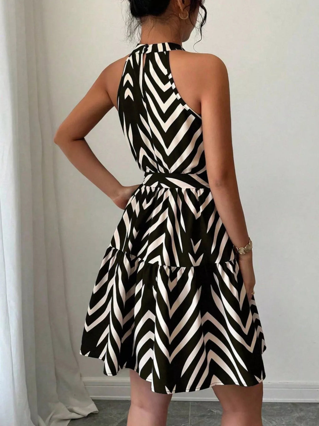 Back view of black zebra-print halter tie-waist dress with ruffle hem and gathered skirt