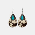 Turquoise teardrop earrings with cow print dangles and silver hooks, studio isolated