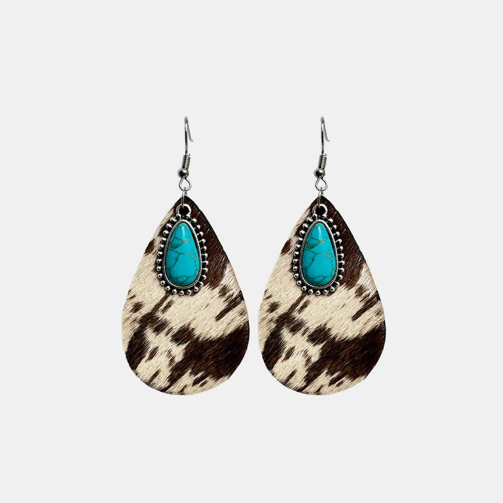 Turquoise teardrop earrings with cow print dangles and silver hooks, studio isolated