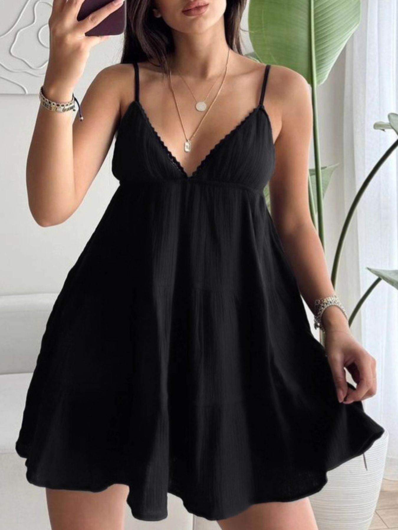 Black V-neck tiered mini dress with lace-trim V neckline and spaghetti straps