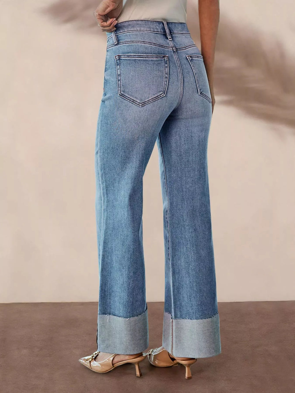 Back view of light blue high-waisted flare jeans with rear pockets and frayed hem