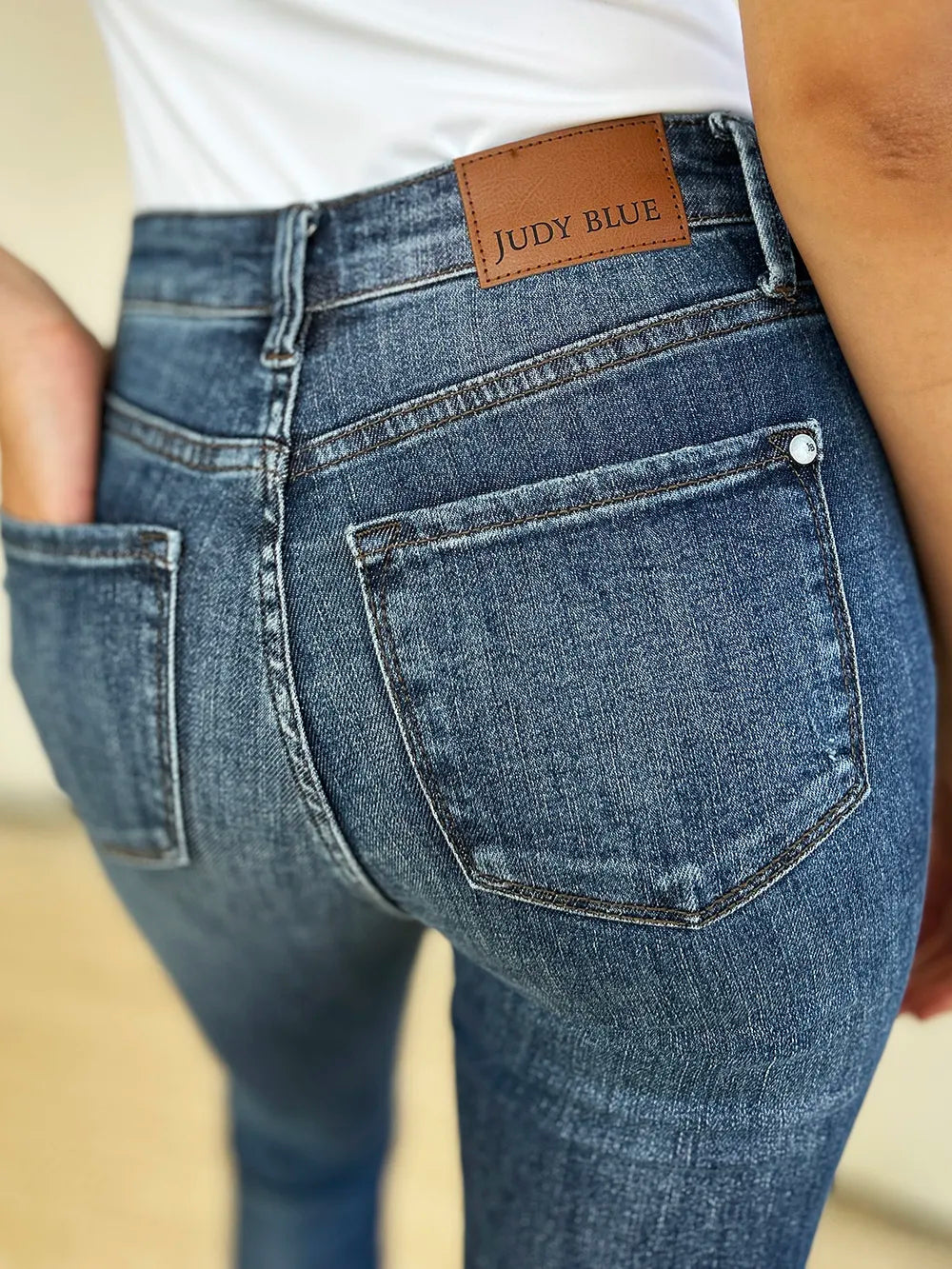 Back yoke and pocket of dark blue jeans with Judy Blue label and distressed wash